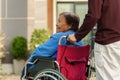 Grandson pushing happy senior woman in wheelchair at outside house Royalty Free Stock Photo