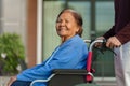 Grandson pushing happy senior woman in wheelchair at outside house Royalty Free Stock Photo