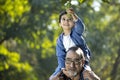 Grandson sitting on grandfather`s shoulder at park