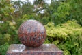 Granite ball on a background of green foliage.