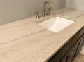 Granite countertop with white sink and chrome faucet on dark wood cabinets, tile floor inside bathroom