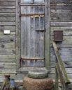 Granite millstones lie in front of the door of a rustic barn Royalty Free Stock Photo