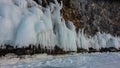 The granite rock at the base is covered with ice splashes, icicles like lace frills.