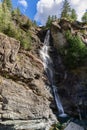 A granite rock covered with sparse vegetation split under endless flowing stream of Lillaz waterfall Cascate di Lillaz