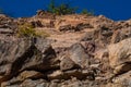 Granite rocks close-up on background blue sky with white clouds, green leaves on treetops. Royalty Free Stock Photo