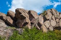 Granite rocks close-up on background blue sky with white clouds, green leaves on treetops. Royalty Free Stock Photo