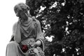 Granite statue of woman holding a red rose at gravesite