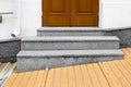 Granite threshold at the entrance door made of brown wood and white facade. Royalty Free Stock Photo