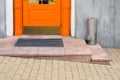Granite threshold with foot mat near orange wooden front door.