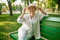 Granny in hat sitting on the bench in summer park