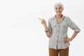 Granny knows something. Portrait of joyful and delighted happy self-assured senior woman with white hair holding hand on