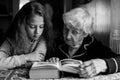 Granny with a little granddaughter reading a book. Help. Royalty Free Stock Photo