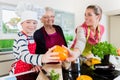 Granny, mum and son talking while cooking in kitchen Royalty Free Stock Photo