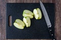 Granny Smith apple quartered on a black cutting board with a chef knife Royalty Free Stock Photo