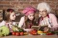 Granny with two granddaughters reading recipe Royalty Free Stock Photo