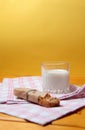 Granola bar and a glass of milk on a towel on wooden table against yellow background Royalty Free Stock Photo