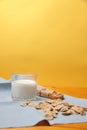 Granola bar, pile of corn flakes and a glass of milk on a towel on wooden table against yellow background Royalty Free Stock Photo