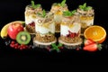 Granola, slices of different fresh fruits, yogurt, honey in jars isolated on black background. Royalty Free Stock Photo