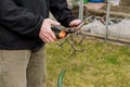 Granpa with black jacket trimming small branches into a barrel. Spring work. First job. Worker cuts woods