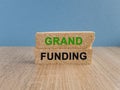Grant funding symbol. Concept green words Grant funding on brick blocks. Beautiful wooden table blue background. Business and