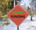 Grant funding symbol. Concept words Grant funding on beautiful red road sign. Beautiful forest snow blue sky background. Business Royalty Free Stock Photo