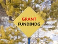 Grant funding symbol. Concept words Grant funding on beautiful yellow road sign. Beautiful forest snow blue sky background. Royalty Free Stock Photo