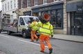 Two workers on their back carrying road traffic cones stacked on each other on their shoulder. Royalty Free Stock Photo
