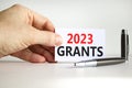 2023 Grants symbol. White paper with words 2023 Grants. Businessman hand. Metallic pen. Beautiful white table white background.