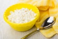 Granular cottage cheese in bowl, yellow napkin, spoon on table Royalty Free Stock Photo