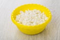 Granular fatless cottage cheese in yellow plastic bowl on table Royalty Free Stock Photo