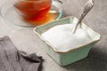 Granulated white sugar in a sugar bowl and a glass cup of tea on the table Royalty Free Stock Photo