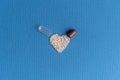 Granules poured from a heart-shaped capsule on a classic blue background. Heart shaped medicines. Heart symbol drawn by Royalty Free Stock Photo