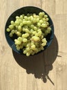 A bowl of grapes basks in the sun and rests on wooden planks Royalty Free Stock Photo