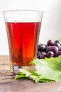 Grape juice and a cluster of grapes with green leaves. Royalty Free Stock Photo