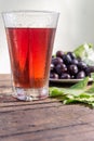 Grape juice and a cluster of grapes with green leaves. Royalty Free Stock Photo