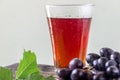 Grape juice and a cluster of grapes with green leaves. Royalty Free Stock Photo