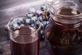 Grape juice in jug, black grapes on the table close up