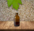 Grape leaf from which a drop of liquid falls into brown bottle Royalty Free Stock Photo