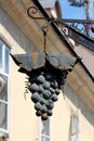 Grape like partially rusted dark wrought iron sign mounted on side of suburban family house in narrow street