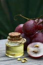 Grape seed oil in a glass jar and fresh grapes on old wooden table in the garden.Spa,bodycare,Bio,Eco products concept. Royalty Free Stock Photo