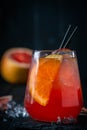 Grapefruit cocktail with Gin or vodka in a clear glass with ice on a black wooden background Royalty Free Stock Photo