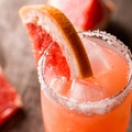 Grapefruit cocktail with ice and salt on a wooden background. Party time. square