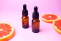 Grapefruit essential oil in glass brown dropper bottles on pink background with fresh fruit, cosmetics and spa Royalty Free Stock Photo