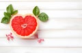 grapefruit fruit slice heart shape and leaves on white wooden table top view