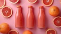 Grapefruit juice bottles with fresh grapefruit halves on a pink surface. Royalty Free Stock Photo