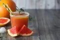 Grapefruit juice in glass and fresh grapefruits on grey wooden table. With copy space Royalty Free Stock Photo