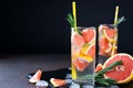 Grapefruit lemonade. Two glasses of refreshing drink, water with grapefruit, rosemary branches and ice.