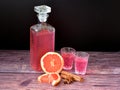 Grapefruit liqueur with cinnamon and anise, strong homemade alcohol in a crystal decanter and two glasses on a dark wooden table Royalty Free Stock Photo