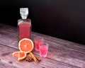 Grapefruit liqueur with spices on a wooden table, strong homemade alcohol in a bottle and two shot glasses with cinnamon, anise Royalty Free Stock Photo