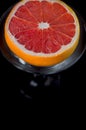 Grapefruit in a martini glass on a black background.